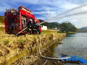 川の水を放水する消防隊