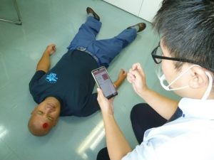 怪我人(左)を見つけ、Net119で通報する利用者(右)